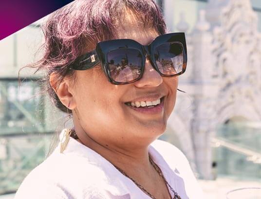 A portrait of Suzanne Hoyem outdoors, smiling with sunglasses on at a CIRE event