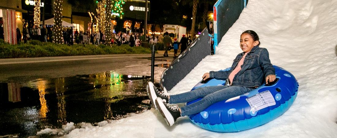 Frosty Fest Park West Event a young girl tubing down a snowy hill